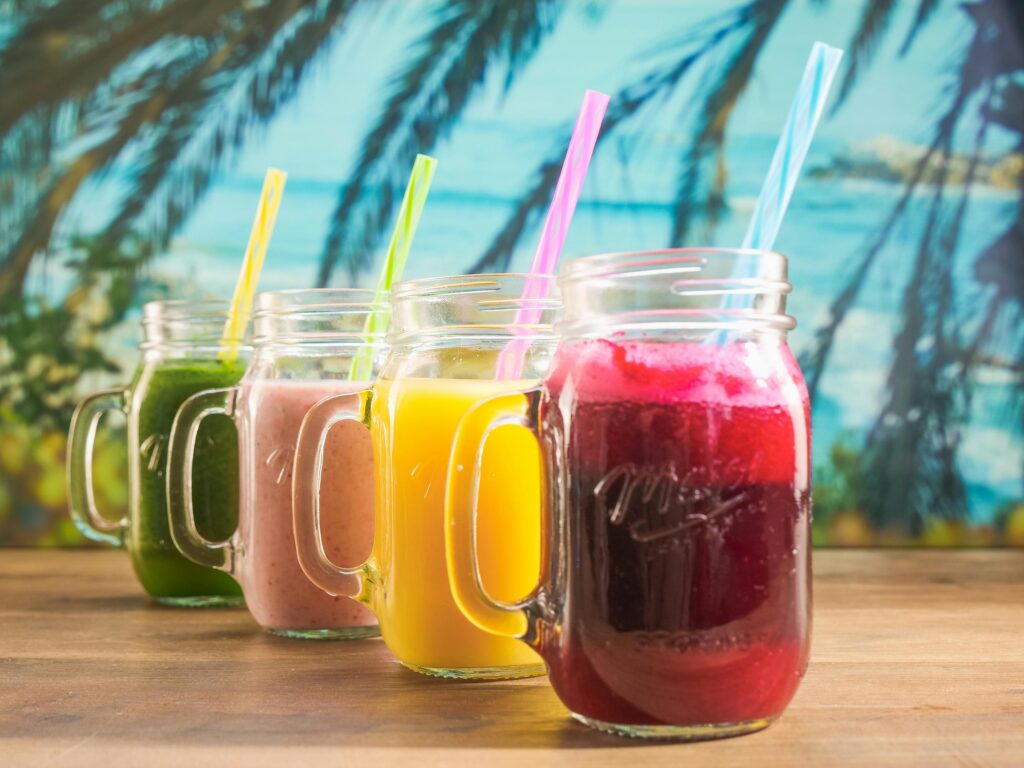 Vibrant fruit juices in mason jars with colorful straws, perfect for a summer refreshment.