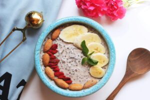 A fresh and delicious chia pudding bowl topped with bananas, almonds, and mint leaves.