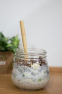 Delicious overnight oats with chia seeds and milk in a jar on a wooden surface.