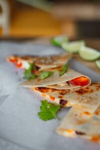 Close-up of freshly made quesadillas with cheese and vegetables served with lime wedges.