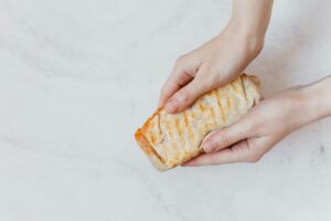 Close-up of hands holding a freshly made burrito with grill marks, ready to eat.